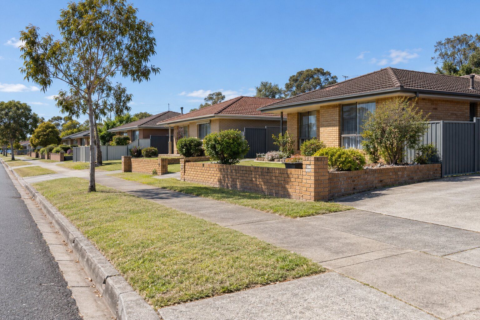 Fencing, Rutherford: a street of 1970s and 1980s brick homes with low brick front fences and grey steel side fences
